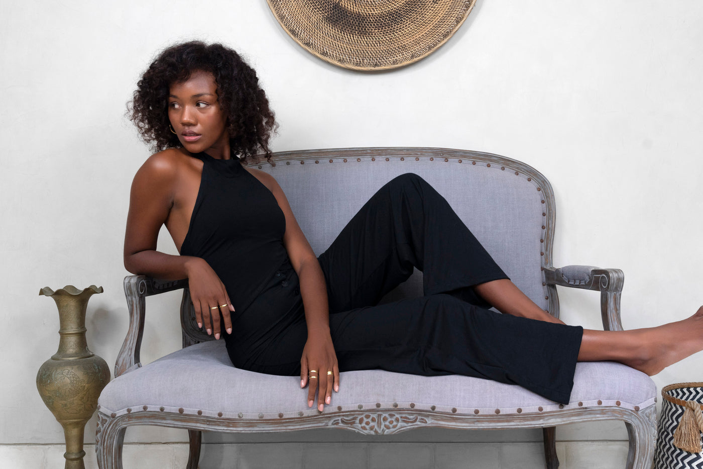 Woman on lounge couch wearing black halter top and black comfy trousers from Ekoluxe sustainable loungewear brand.