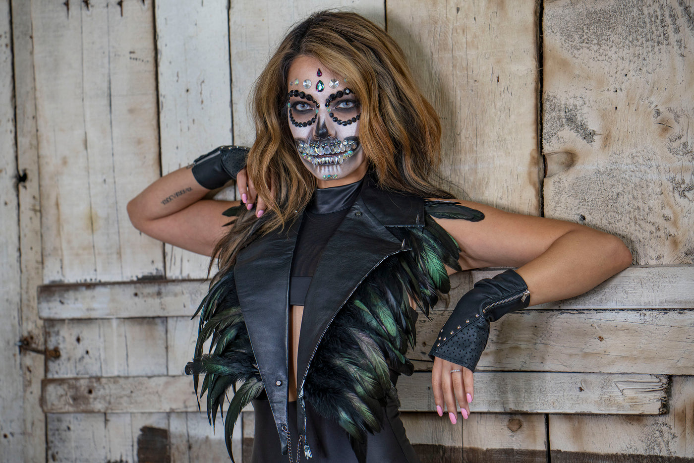 Woman with dia de los muertos makeup in leather collar festival top with feathers and fingerless leather gloves by Love Khaos Festival Clothing