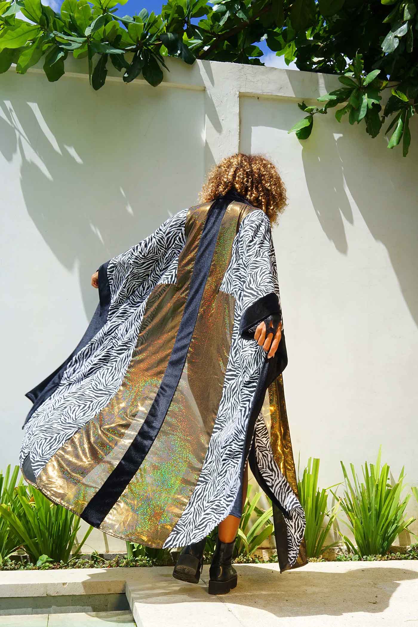 A woman wearing a gold and black velvet kimono from Love Khaos.