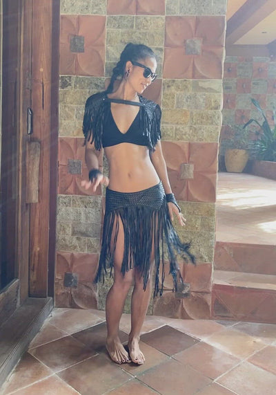 Woman dancing in woven leather fringe skirt from Love Khaos festival clothing brand.